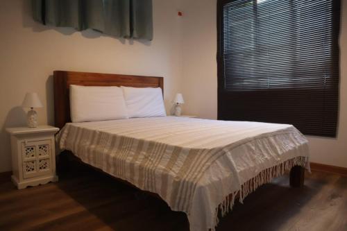 a bedroom with a bed with a night stand and a window at Maison des Anges in Mahébourg