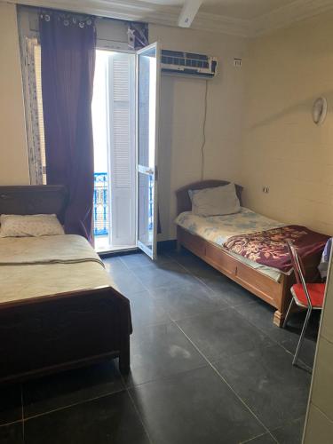 a room with two beds and a window with a door at Hôtel Agriculture in Tunis