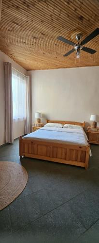 a bedroom with a wooden bed and a ceiling fan at By Karin in Kranevo