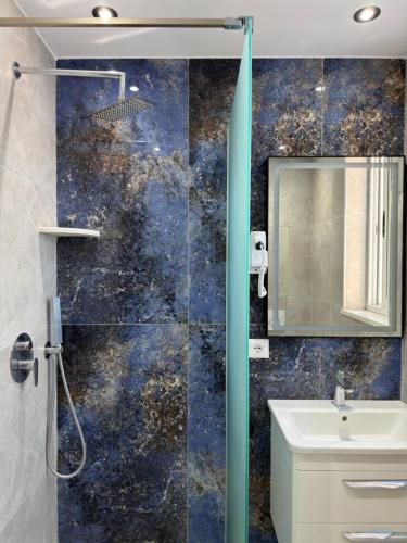 a bathroom with a shower and a sink and a mirror at Hotel De La Playa in Velipojë