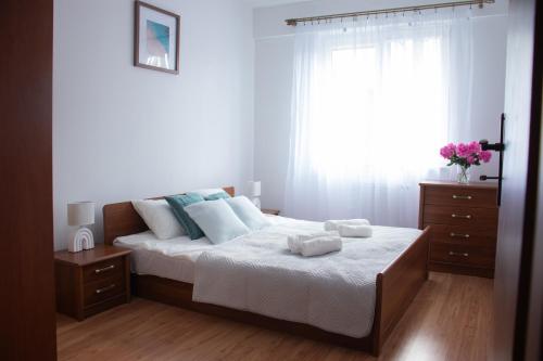 a bedroom with a bed with white sheets and a window at Płock City Center Apartment in Płock