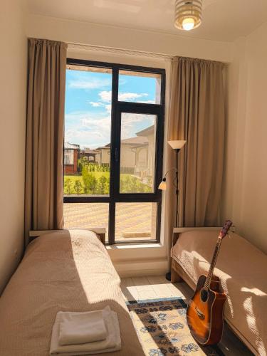 a bedroom with a guitar in front of a window at Nomad Resort Cholpon-Ata in Cholpon-Ata