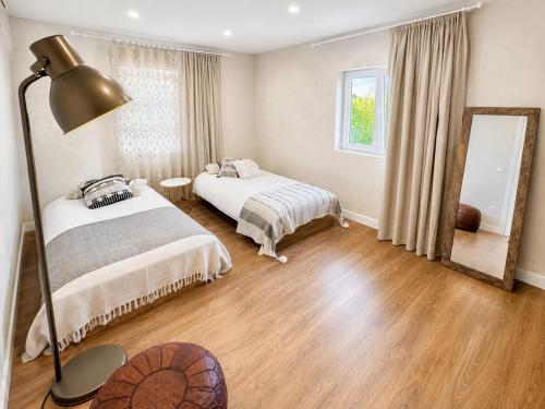 a bedroom with two beds and a lamp and a mirror at Retiro São Pedro House in Aldeia da Mata