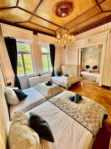 a bedroom with two beds and a chandelier at Villa Sartorius - charmant und denkmalgeschützt wohnen nahe Göttingen in Bovenden
