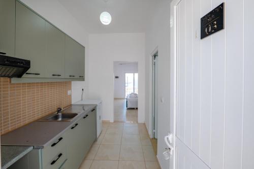 a kitchen with white cabinets and a sink and a hallway at The Hidden Sea Rooms in Sarandë