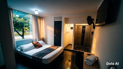 a small bedroom with a bed and a window at Hotel Aura Nutibara in Medellín