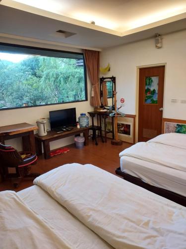a bedroom with two beds and a desk and a window at Hong Wa Cuo南投埔里紅瓦厝山居民宿森林系住宿生態手作體驗 in Puli