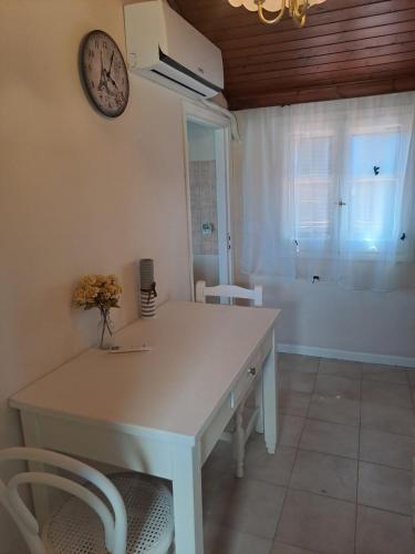 a kitchen with a white table and a clock on the wall at Retire Alefkimmon in Lefkimmi