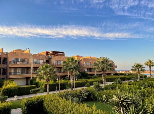 an apartment building with palm trees and a garden at 396 Blumar Chalet North Coast Sidi-abdelrahman families & couples only in El Alamein