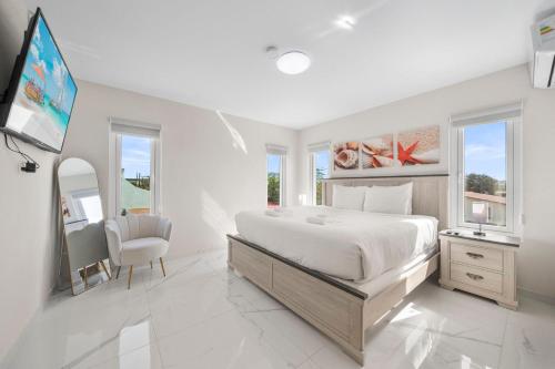 a white bedroom with a large bed and a tv at Monserat 33Q in Palm-Eagle Beach