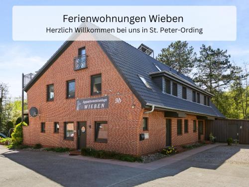a red brick building with a black roof at Ferienwohnung Wieben Sankt Peter-Ording in Böhl