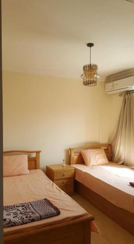 a bedroom with two beds and a chandelier at Chalet with roof pool view in Dawwār ‘Abd Allāh