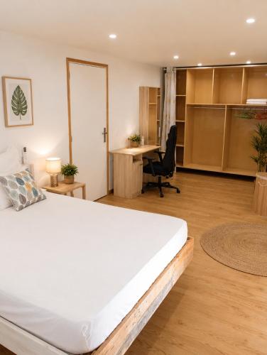 a bedroom with a large white bed and a desk at Kaz an Fanmi in Les Abymes