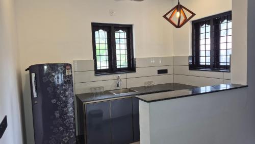 a kitchen with a black refrigerator and a sink at Casa Luminaria in Alleppey