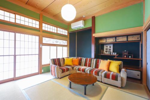 a living room with a couch and a table at サウナ&ステイ吉日荘-益子町のプライベートサウナ付の貸切古民家 BBQ 高速Wi-fi in Mashiko