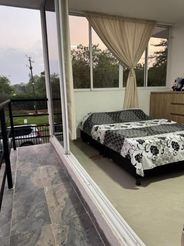 a bedroom with a bed on a balcony with windows at El Chaparral in Yopal