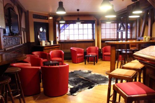 a bar with red chairs and tables in a room at A la Maison Rouge Hôtel & Restaurant in Barr