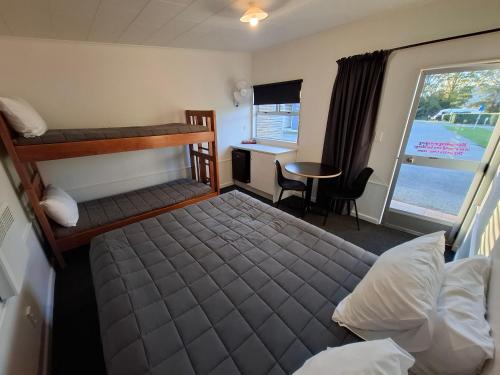 a bedroom with two bunk beds and a desk at Spring Creek Holiday Park in Blenheim