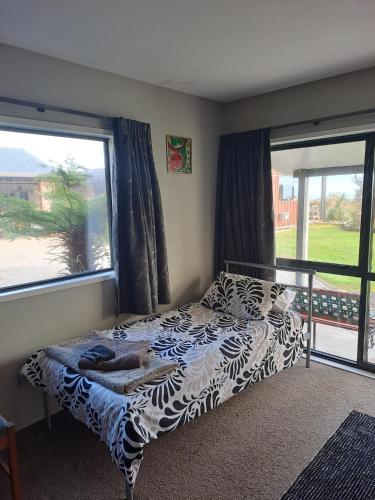 a bedroom with a bed and two large windows at Koru Beachfront Holiday Cabins & Hot Tub in Barrytown