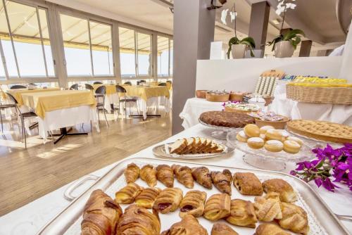 a table filled with different types of pastries and pies at Hotel Tirreno in Spotorno