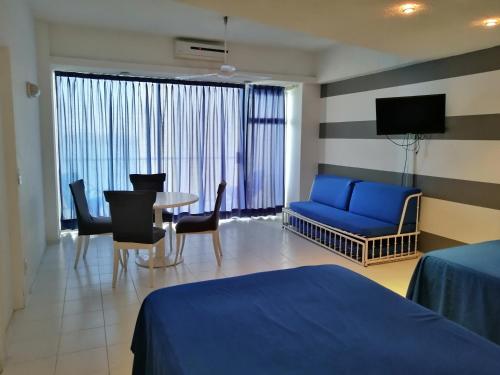 a hotel room with a blue bed and a table and chairs at Hermosa Suite Torres Gemelas in Acapulco