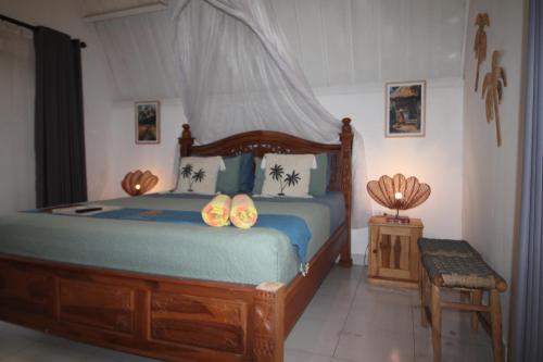 a bedroom with a bed with two flip flops on it at New Balengku Dua Hotel - Adults Only in Gili Islands