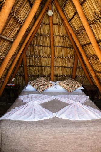 a bed in a thatch roofed bedroom at Aloha Popoyo in Playa Santana