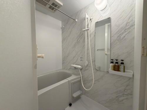 a white bathroom with a tub and a sink at レジデグローバル熊本 in Kumamoto