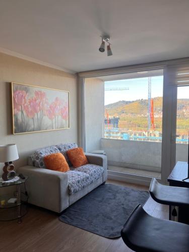 a living room with a couch and a large window at Departamento Los Poetas in Temuco