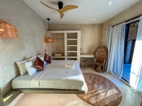 a bedroom with a large bed and a fan at Happiness Kulambo Villa El Nido in El Nido