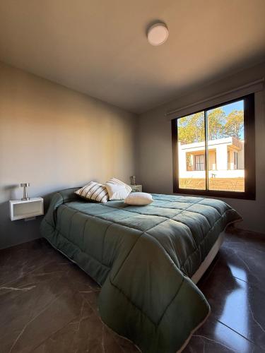 a bedroom with a large bed with a large window at El Tesoro de Yacanto in Villa Yacanto