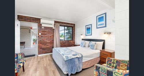 a bedroom with a bed and two chairs at A&A Lodge Motel in Emerald