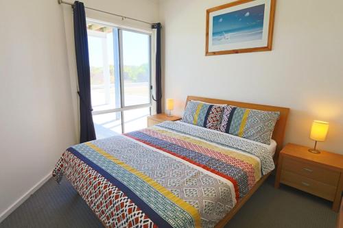 a bedroom with a bed with a window and a bedspread at '128 The Esplanade' - Beachside holiday home with swimming pool in Robe in Robe