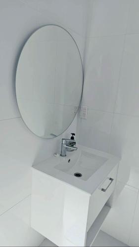 a white bathroom with a mirror and a sink at Mama's Mountain Views in Avarua
