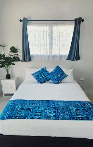 a white bed with blue sheets and a window at Mama's Mountain Views in Avarua