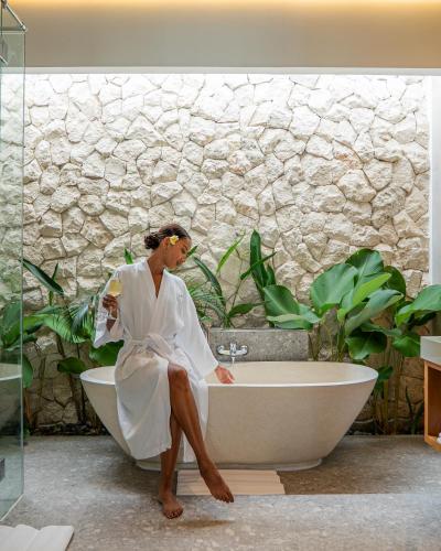 a woman sitting in a bath tub in a bathroom at Lomo Boutique Hotel & Villas, Uluwatu in Uluwatu