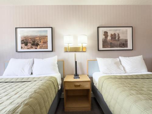 two beds in a hotel room with two lamps at Prospector Inn in Escalante