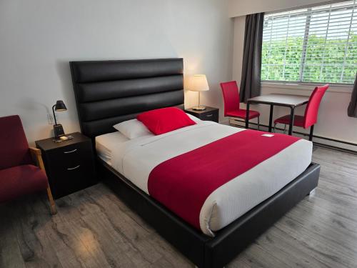 a bedroom with a large bed with a red and white blanket at Alpine Motel in Hope