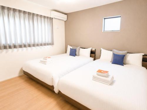 two beds in a room with white and blue pillows at Burikina Terrace in Nago