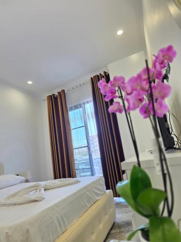a bedroom with a bed and a vase with purple flowers at Crown Villa in Golem