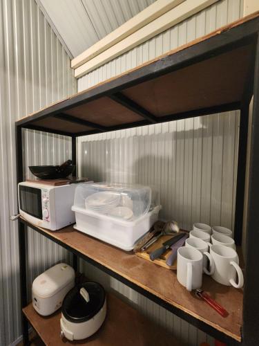 a kitchen shelf with a microwave and other appliances at Porjai's Lakeview in Phetchabun