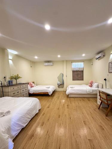 a room with three beds and a wooden floor at Dune House Phan Thiết in Ấp Bình Hưng