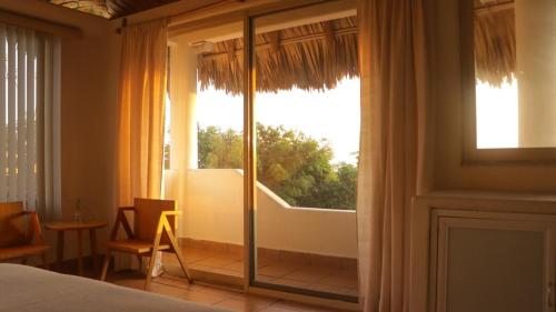 a bedroom with a large window with a view at Aguamiel Manzanillo in Puerto Escondido