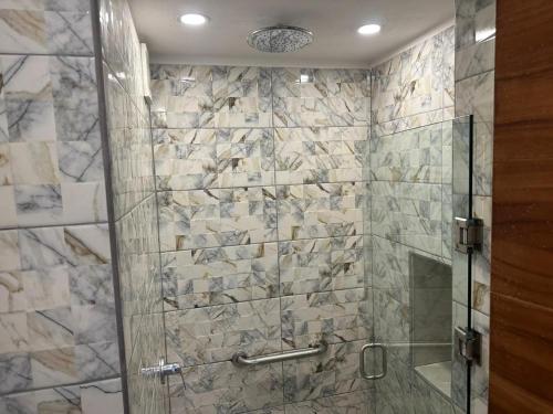 a bathroom with a shower with a glass door at Bungalows Omar Deluxe in Rincon de Guayabitos