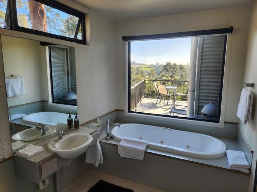 a bathroom with two sinks and a tub with a large window at Tamar Ridge Winery Apartments in Grindelwald