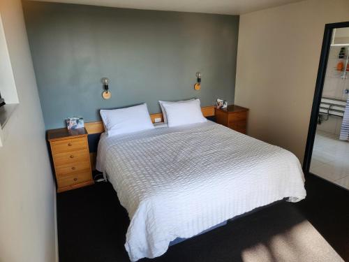 a bedroom with a white bed and a mirror at Tamar Ridge Winery Apartments in Grindelwald