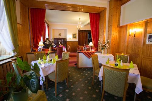 a restaurant with white tables and chairs and red curtains at Hotel Central in Bad Elster