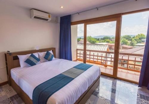 a bedroom with a bed and a large window at The Indigo House Phrae in Ban Rong Fong