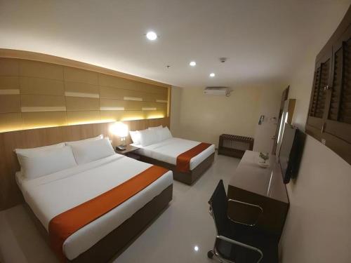 a hotel room with two beds and a desk at Hotel Veniz - Session in Baguio