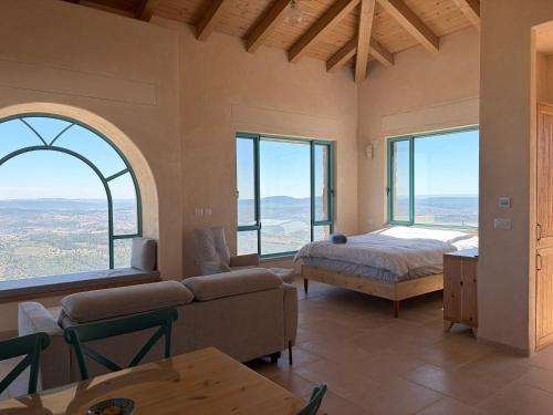 a bedroom with a bed and a couch and windows at מול האופק horizonview in Kammon